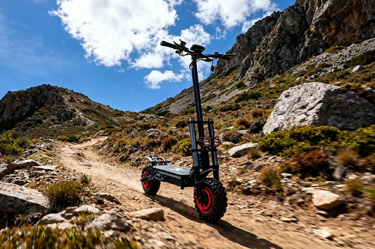 Black-red J30 Max heavy-duty electric scooter with dual front lamp setup, thick deep-tread off-road tyres and heavy-duty dual suspension, navigating uneven dusty alpine path amid jagged rocky cliffs and wild mountain shrubs